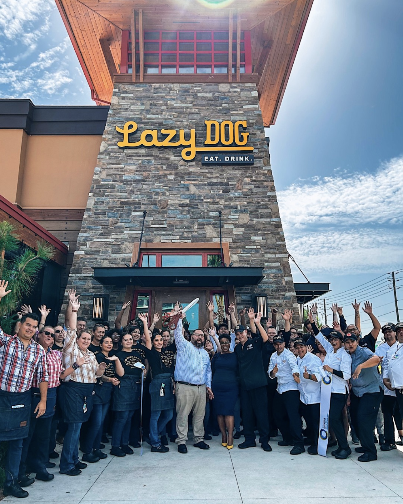 front of lazy dog restaurant building with people cutting opening ribbon 